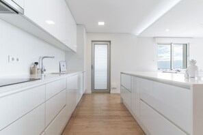 Una cocina moderna con armarios blancos, piso de madera y vistas a través de un ventanal.