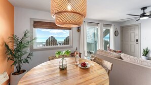 A dining area with a wooden table, a bottle of wine, and a plate of fruit. - Flamingo Cove  | by Pitzer-Properties (Port St. Joe)