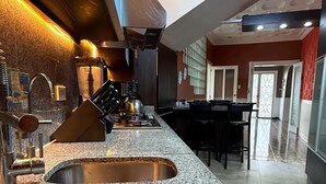 A modern kitchen with stainless steel sinks, a built-in stove, and a dining area with a table and chairs.