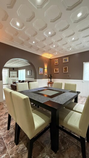 A dining area with a rectangular table, six chairs, and a decorative ceiling.