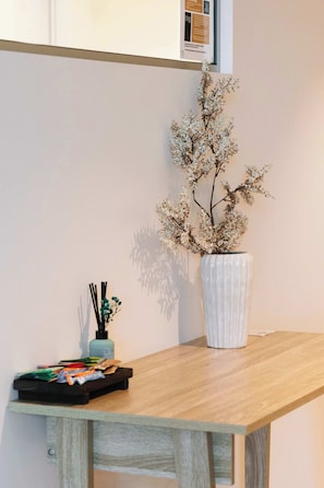 A wooden table with a white vase containing dried branches, a small blue bottle, and a tray with colorful items. - ST Apartments by Arvia Living (Brisbane City)