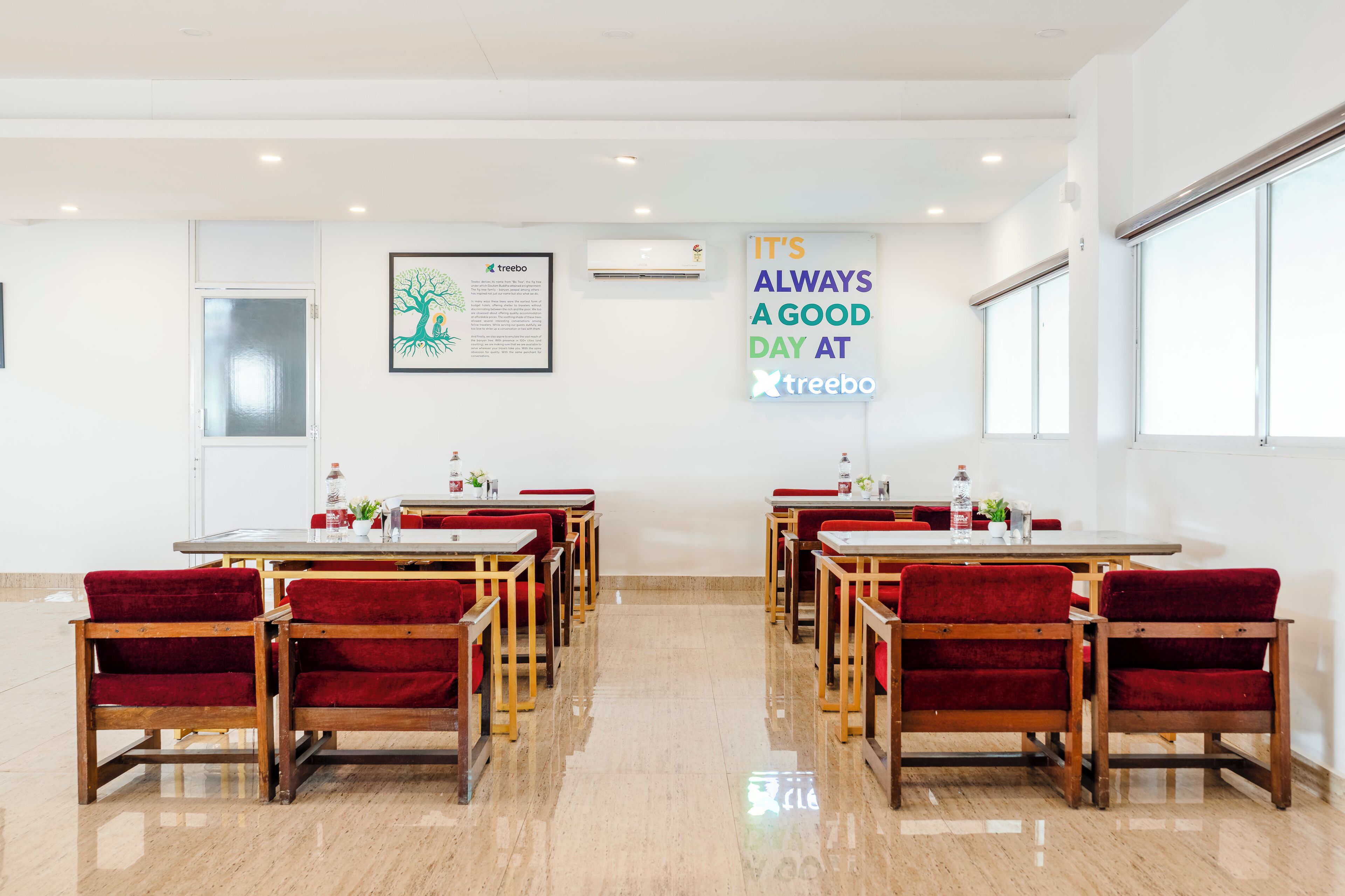 Un área de comedor con mesas y sillas, un letrero en la pared y un cuadro enmarcado.