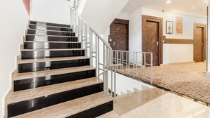 Una scala moderna con ringhiere in metallo e pavimento decorato che conduce a una porta in legno.
