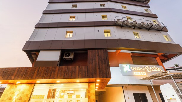 Un hotel a più piani dal design moderno, con il cartello Skyline Hotel, il cartello di Treebo Cafe e un condizionatore d'aria ben visibile.