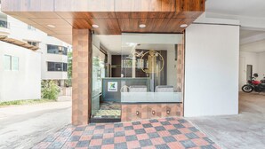 Una zona reception dal design moderno, con soffitto in legno, pavimento a motivi e porta in vetro con un logo.