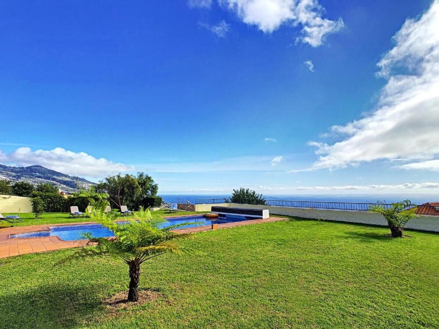 A pool area with a view of the ocean and mountains.