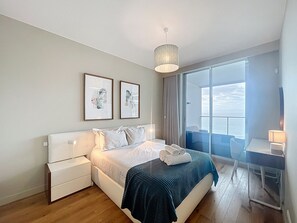 A modern hotel room with a large bed, a desk, and a view of the sea. - Pearl View by Atlantic Holiday (Funchal)