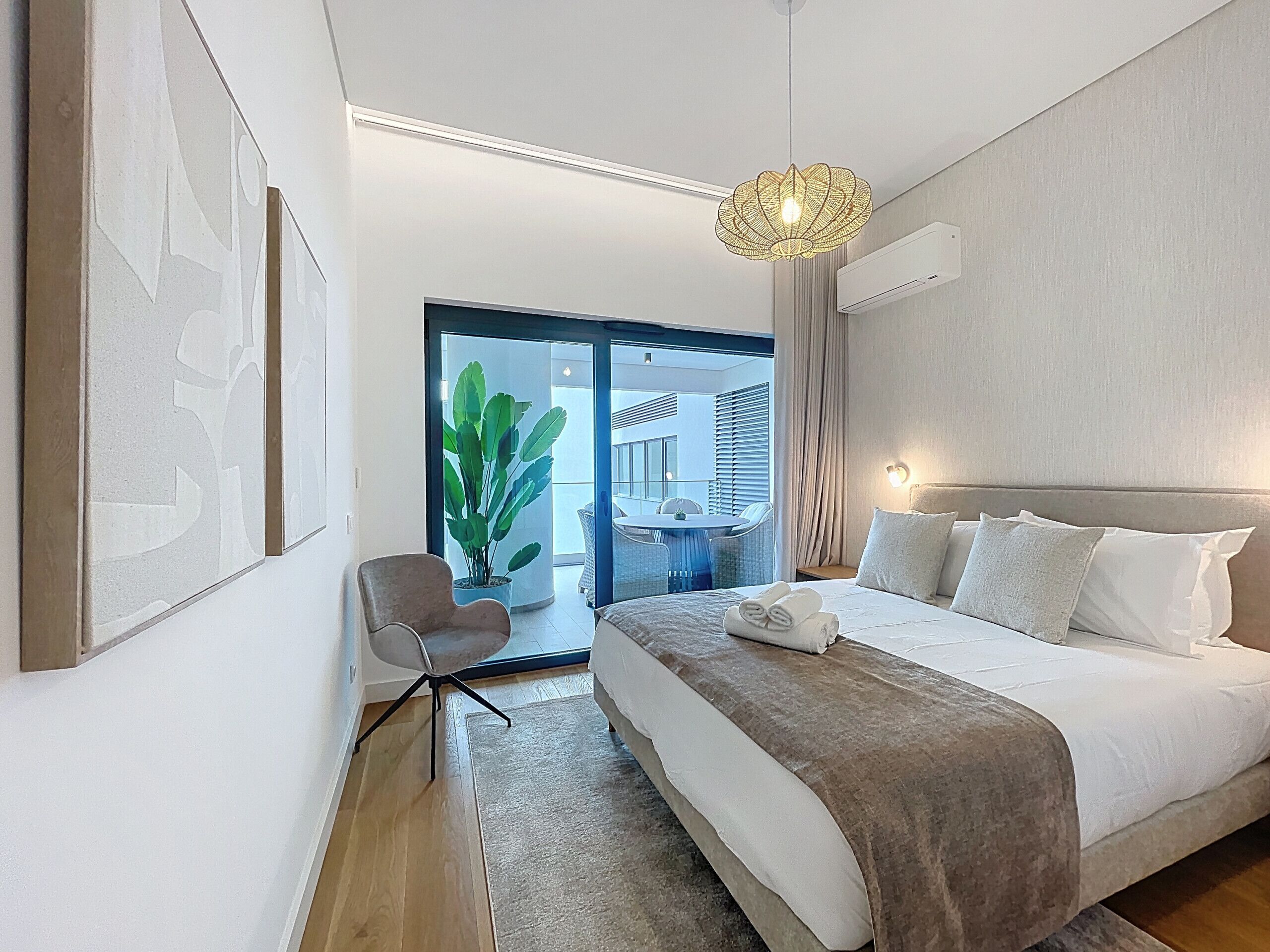 Une chambre d’hôtel moderne, dotée d’un grand lit, d’un bureau, d’une chaise et offrant une vue sur le balcon extérieur.