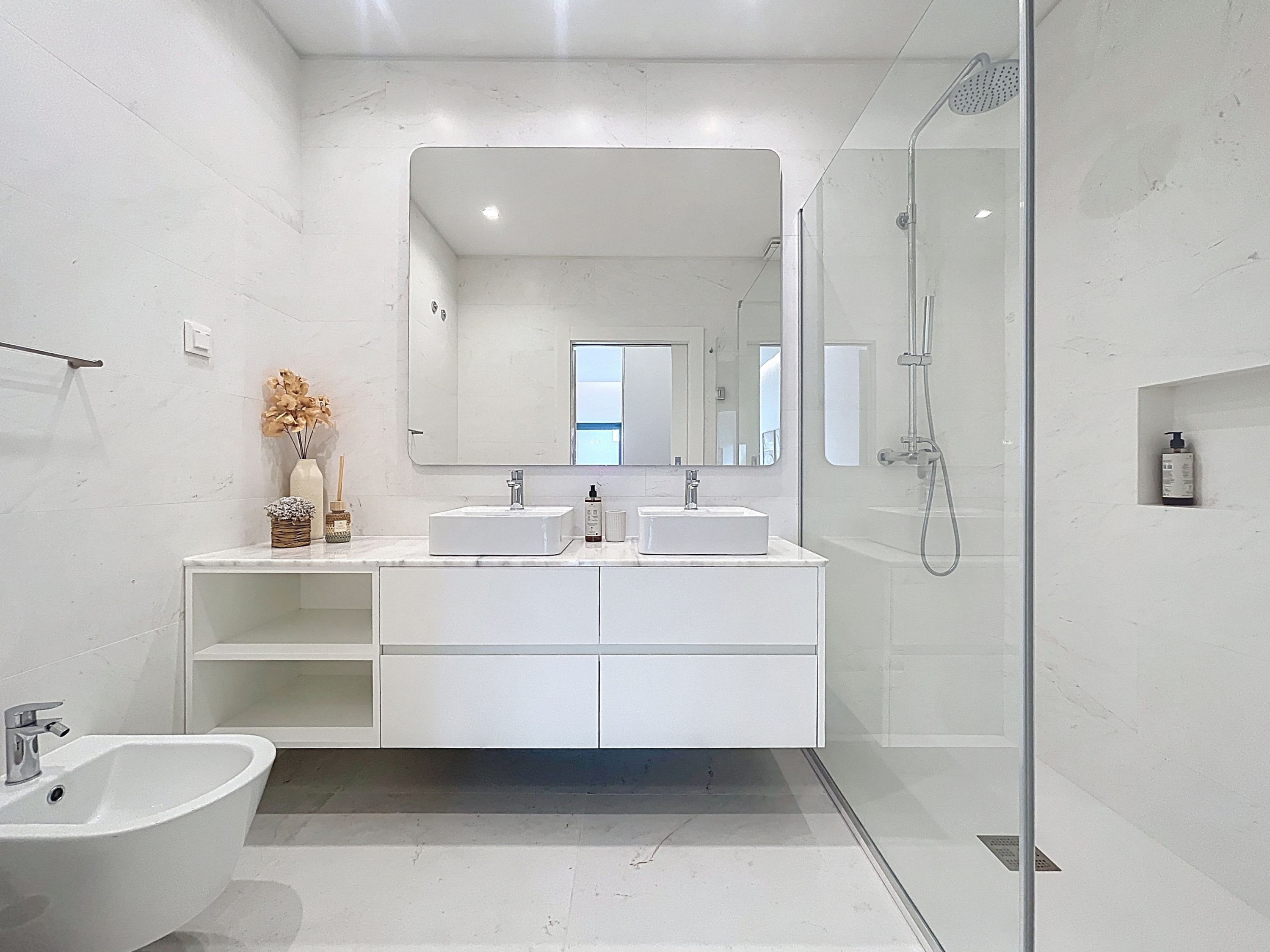 A modern bathroom with a glass-enclosed shower, a freestanding bathtub, and a vanity with two sinks.