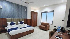 A hotel room with a large bed, a sofa, a desk with a computer, and a window. - Belle Tree Hotel (Greater Noida)