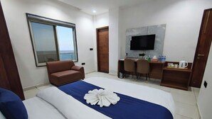 A hotel room with a large bed, a desk with two chairs, a television, and a window with a view. - Belle Tree Hotel (Greater Noida)