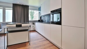Una cocina moderna con armarios blancos, encimera negra y horno empotrado.
