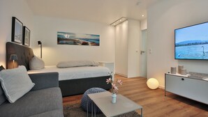 Una habitación de hotel moderna con cama, sofá, televisor y obras de arte en la pared.