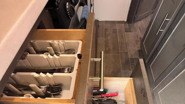 A kitchen with a drawer organizer containing utensils and a cutting board. - Cozy Lux Camper on Quiet Farm (Apopka)
