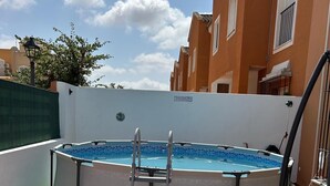 Piscina gonfiabile Bestway Steel Pro Max rotonda, con scaletta, circondata da prato sintetico verde e un patio piastrellato.
