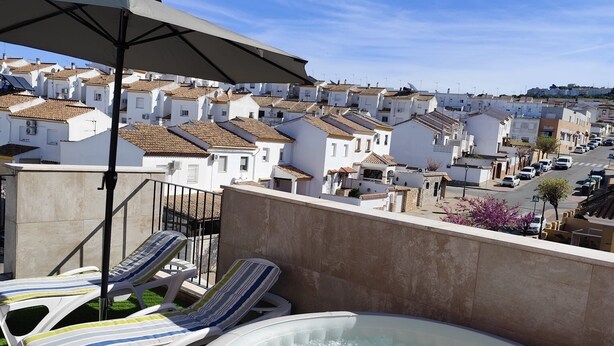 Una terrazza panoramica sul tetto con idromassaggio, poltrone relax e vista su un quartiere residenziale.