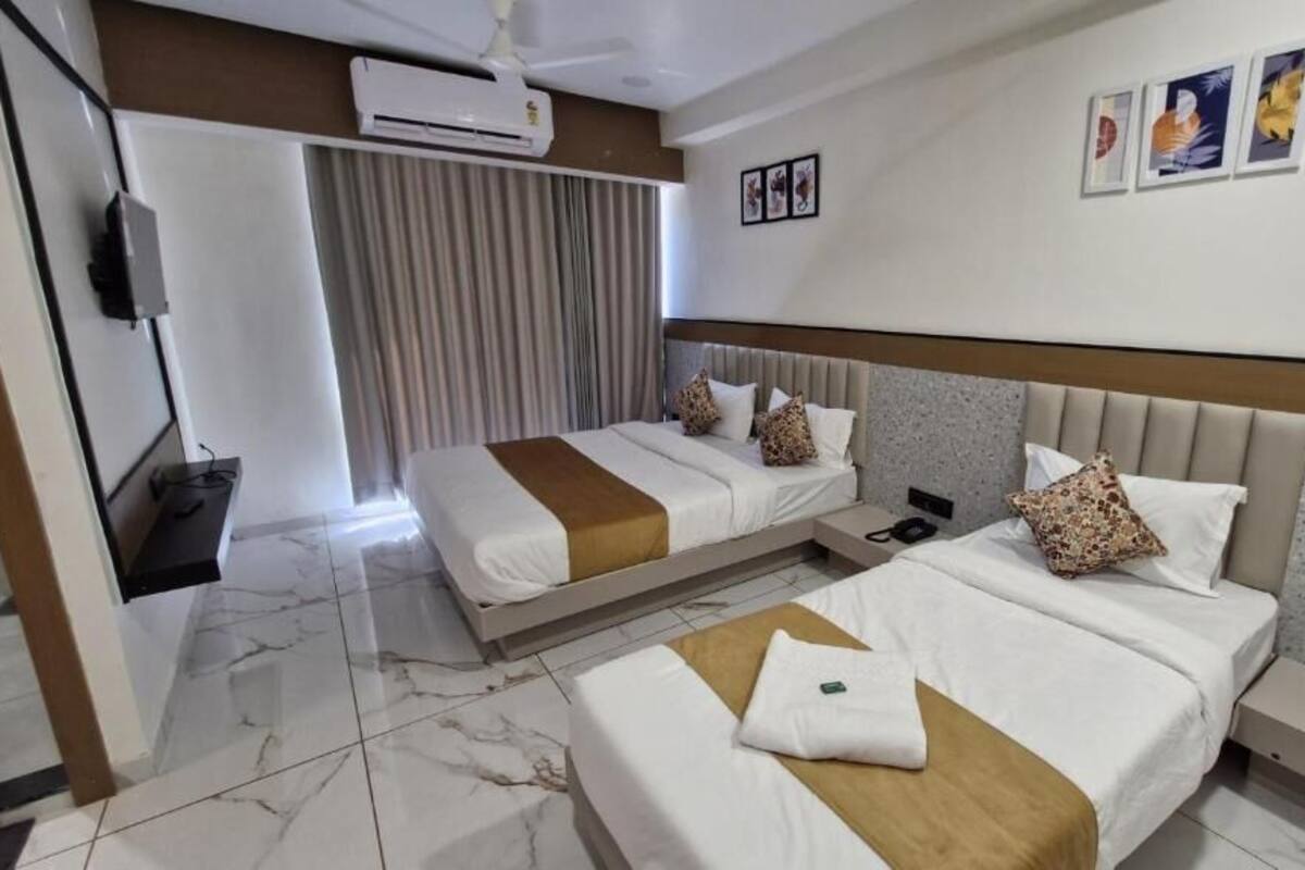 Una camera d'albergo con due letti, una televisione, un condizionatore d'aria e una tenda.