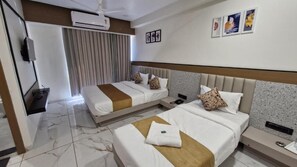 A hotel room with two beds, a TV, an air conditioning unit, and a curtain. - Hotel Rose Gold (Ahmedabad)