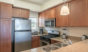 A modern kitchen with wooden cabinets, stainless steel appliances including a refrigerator, microwave, stove, and toaster, and a granite countertop. - Marina Del Rey Getaway - Close To Venice Beach (Marina del Rey)
