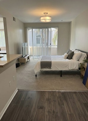 A modern bedroom with a bed, a TV, and a balcony with curtains. - Fantastic Escape In Marina Del Rey - 1 Bedroom (Marina del Rey)