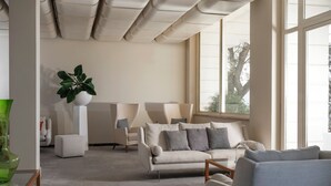 A modern living room with a beige sofa, a coffee table, and a green vase on a glass table. - Europa Grand Hotel  (Lerici)