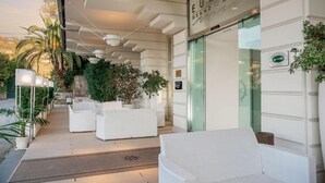 The entrance of the Europ Grand Hotel with white outdoor seating and a glass facade. - Europa Grand Hotel  (Lerici)