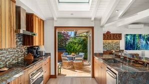 A modern kitchen with wooden cabinets, a built-in oven, and a large island with a sink. - SUMMER SALE! Discover paradise in a 3-bedroom oceanfront getaway - Alaeloa 28 (Lahaina)