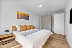 Ein Schlafzimmer mit einem Bett, einem Nachttisch, einer Lampe, einem Bild und einem Kleiderschrank.