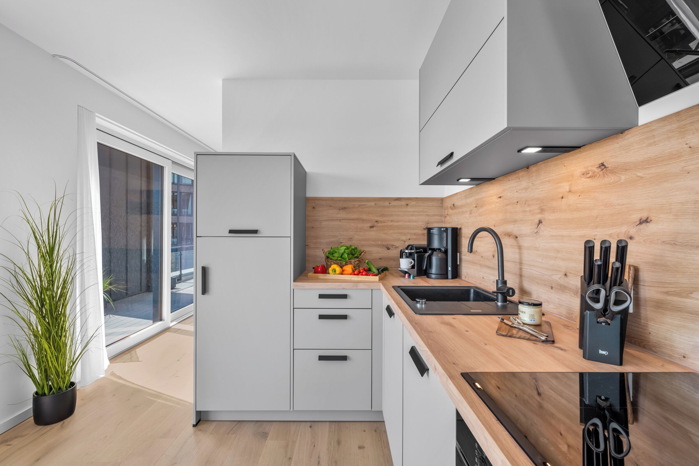 A modern kitchen with a built-in refrigerator, wooden countertop, and a black faucet.