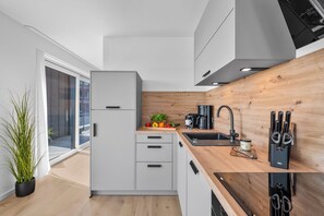 Une cuisine moderne dotée d’un réfrigérateur encastré, d’un plan de travail en bois et d’un robinet noir.