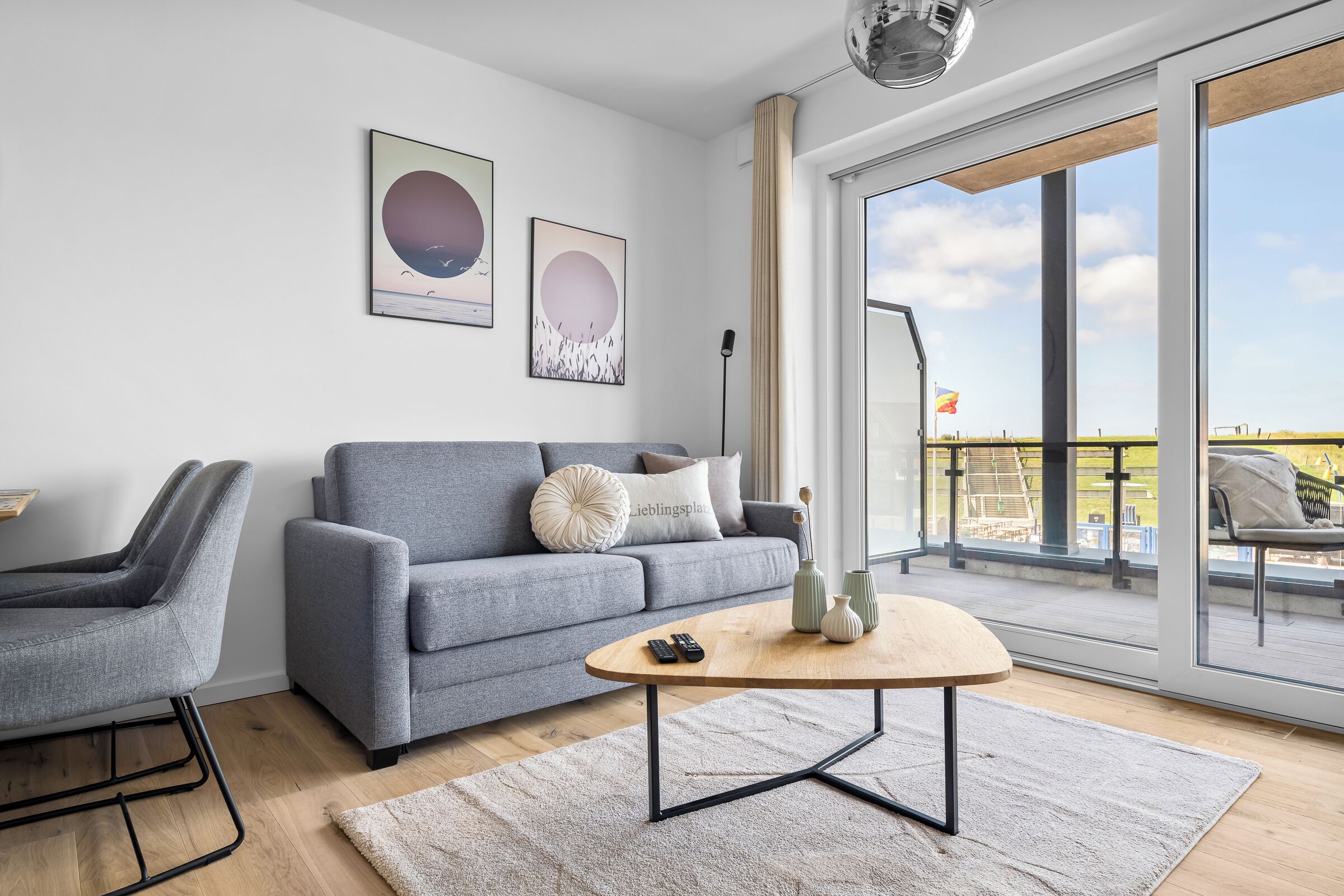 Ein modernes Wohnzimmer mit einem grauen Sofa, einem runden Couchtisch und einem grauen Sessel.