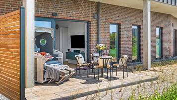 A modern outdoor living area with a sofa, chairs, and a dining table.