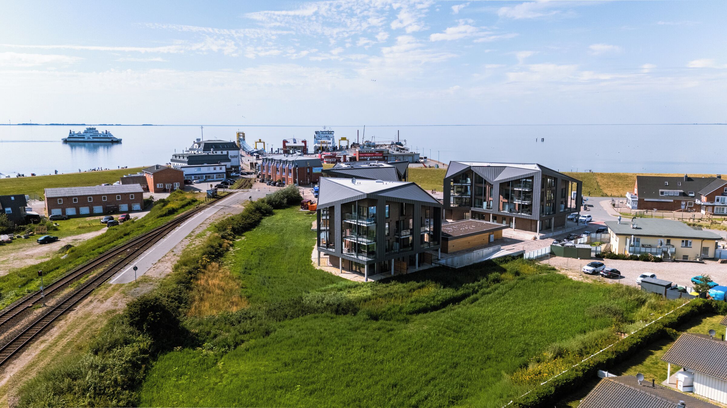 Une ville côtière dotée de bâtiments modernes, d’un port de plaisance et d’une voie ferrée.