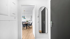Un pasillo con una decoración moderna, un comedor con una mesa redonda y sillas, y un espejo grande en la pared.