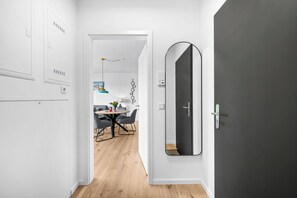 Ein Flur mit modernem Interieur, ein Essbereich mit rundem Tisch und Stühlen sowie ein großer Spiegel an der Wand.