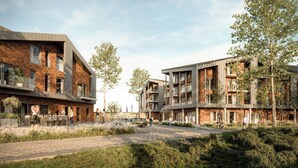 Ett modernt bostadskomplex med fasader i tegel, balkonger och en stenlagd gångväg.