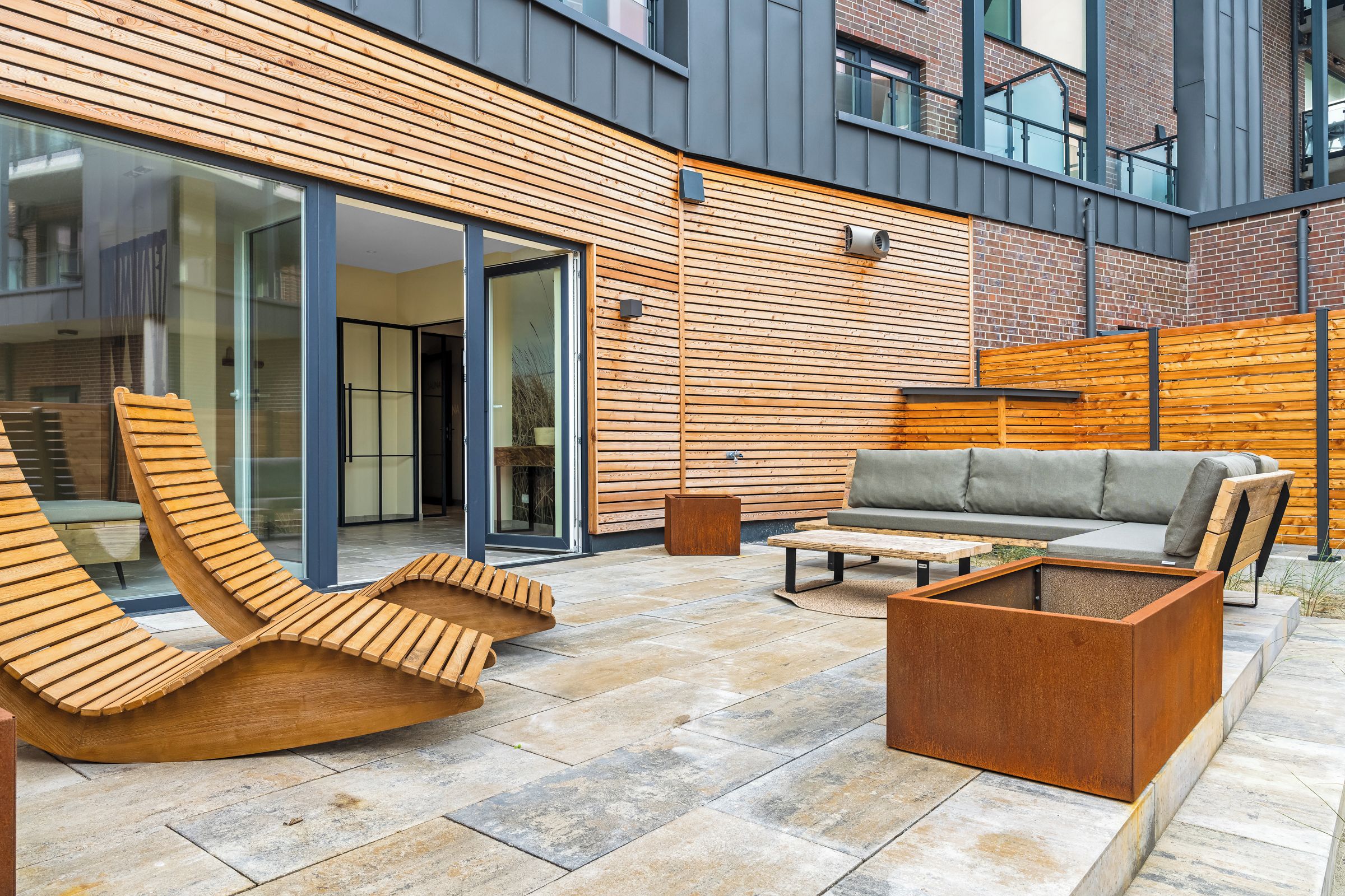 Eine Terrass mit Gartenmöbeln, einer Couch und einem Couchtisch.