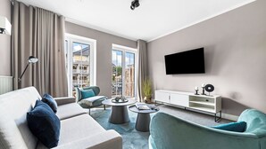 Ett modernt vardagsrum med en soffa, fåtöljer, ett soffbord och en tv.