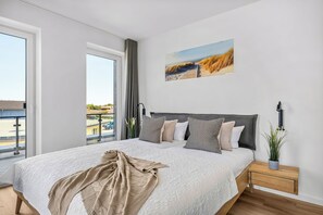 Ein Schlafzimmer mit einem großen Bett, Blick ins Freie und einem Bild an der Wand.
