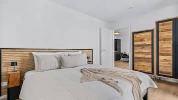 A modern bedroom with a large bed, a bedside lamp, and a wardrobe with a wooden finish.