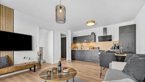 Ein modernes Wohnzimmer mit einer Couch, einem Couchtisch und einem an der Wand montierten Fernseher.