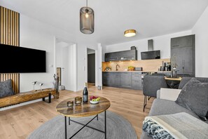 Una sala de estar moderna con un sofá, una mesa de centro y un televisor montado en la pared.