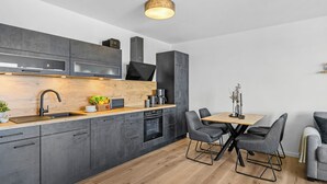 Eine moderne Küche mit grauen Schränken, einer Holzarbeitsplatte und einem eingebauten Backofen.