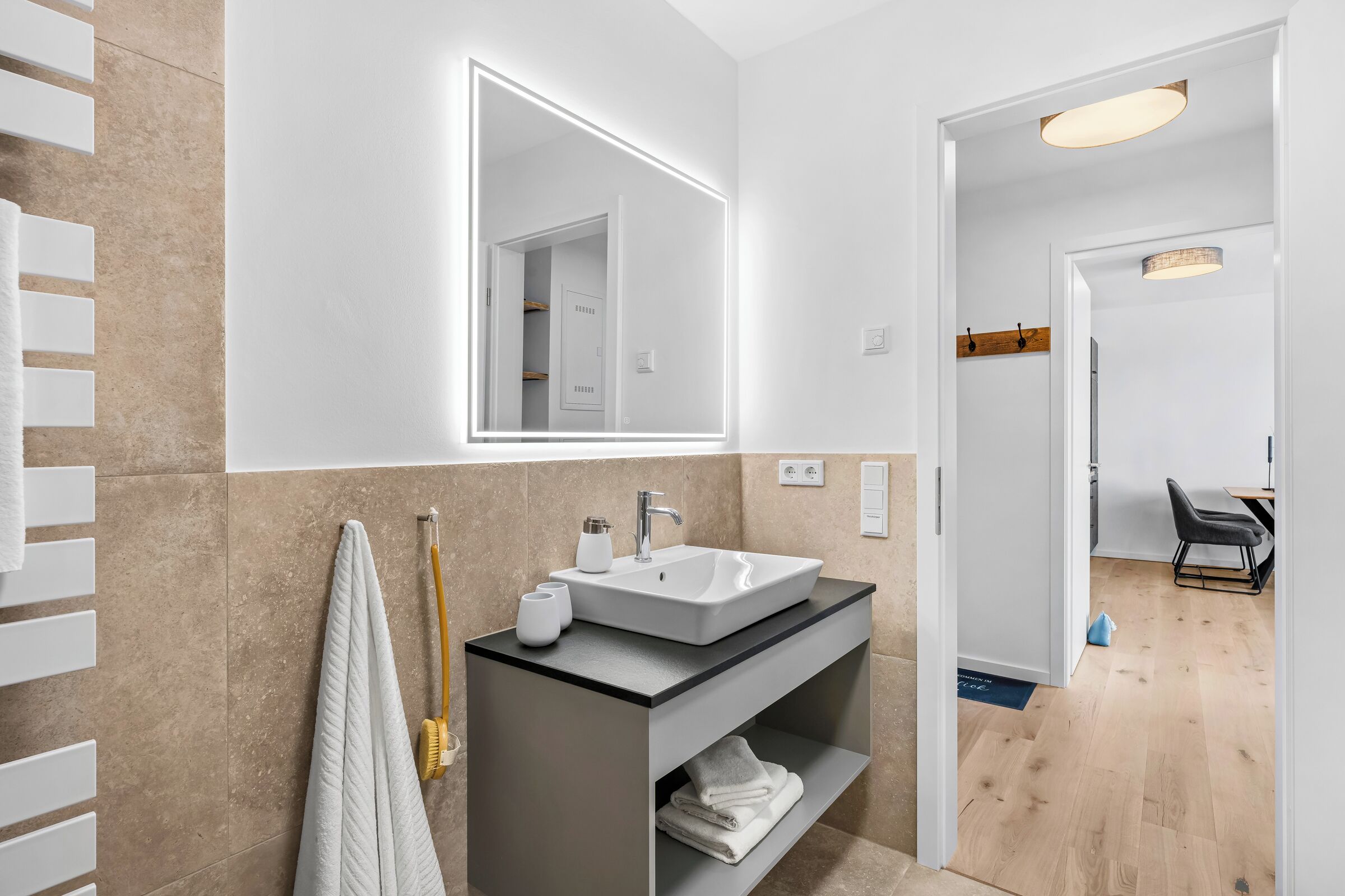A modern bathroom with a large mirror, a sink, and a towel rack.
