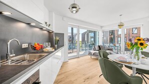 Une cuisine moderne équipée d’un four encastré, d’un évier et d’un coin repas avec une table et des chaises.