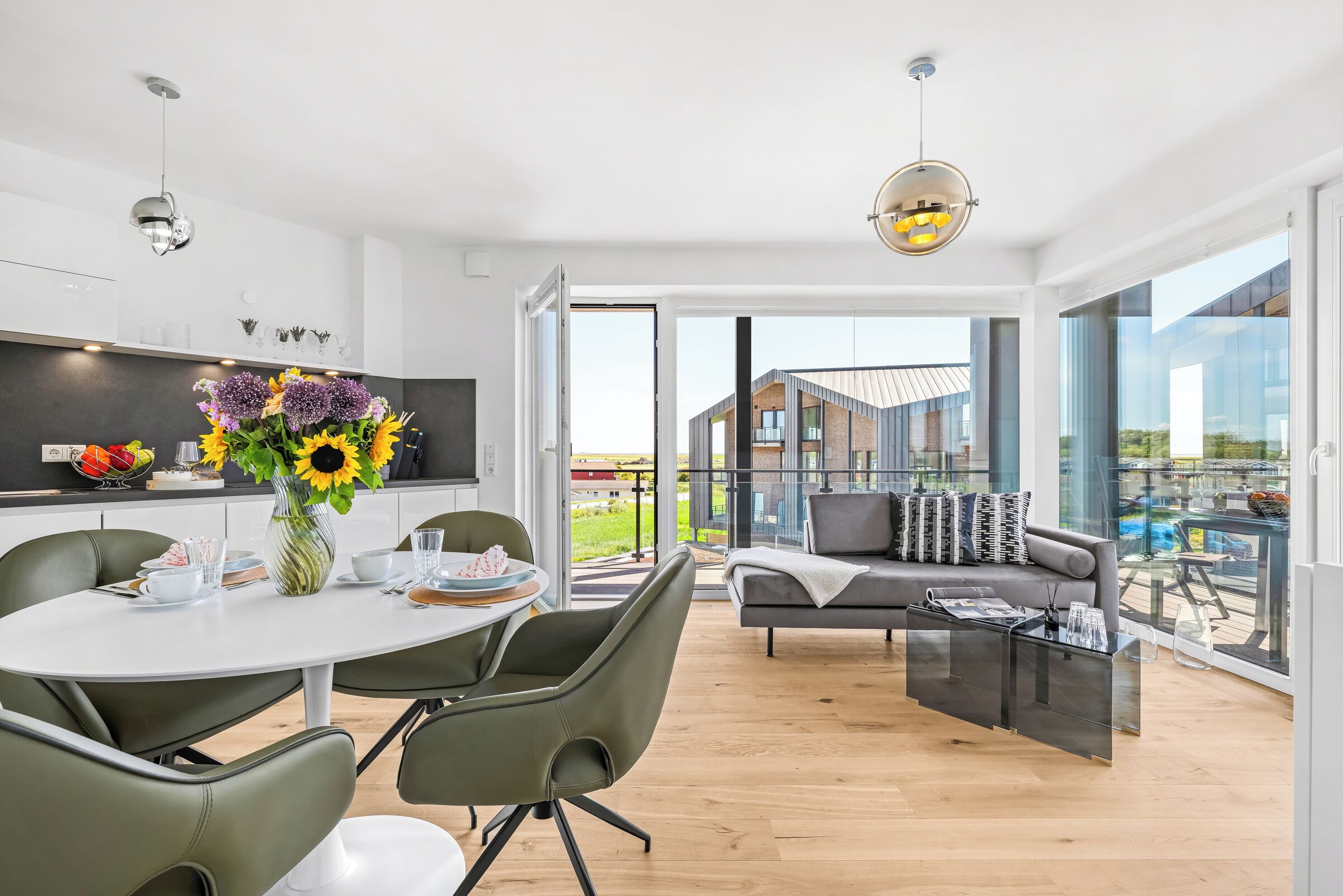 Eine moderne Küche mit Essbereich, einer Couch und einem großen Fenster mit Blick auf ein Gebäude.