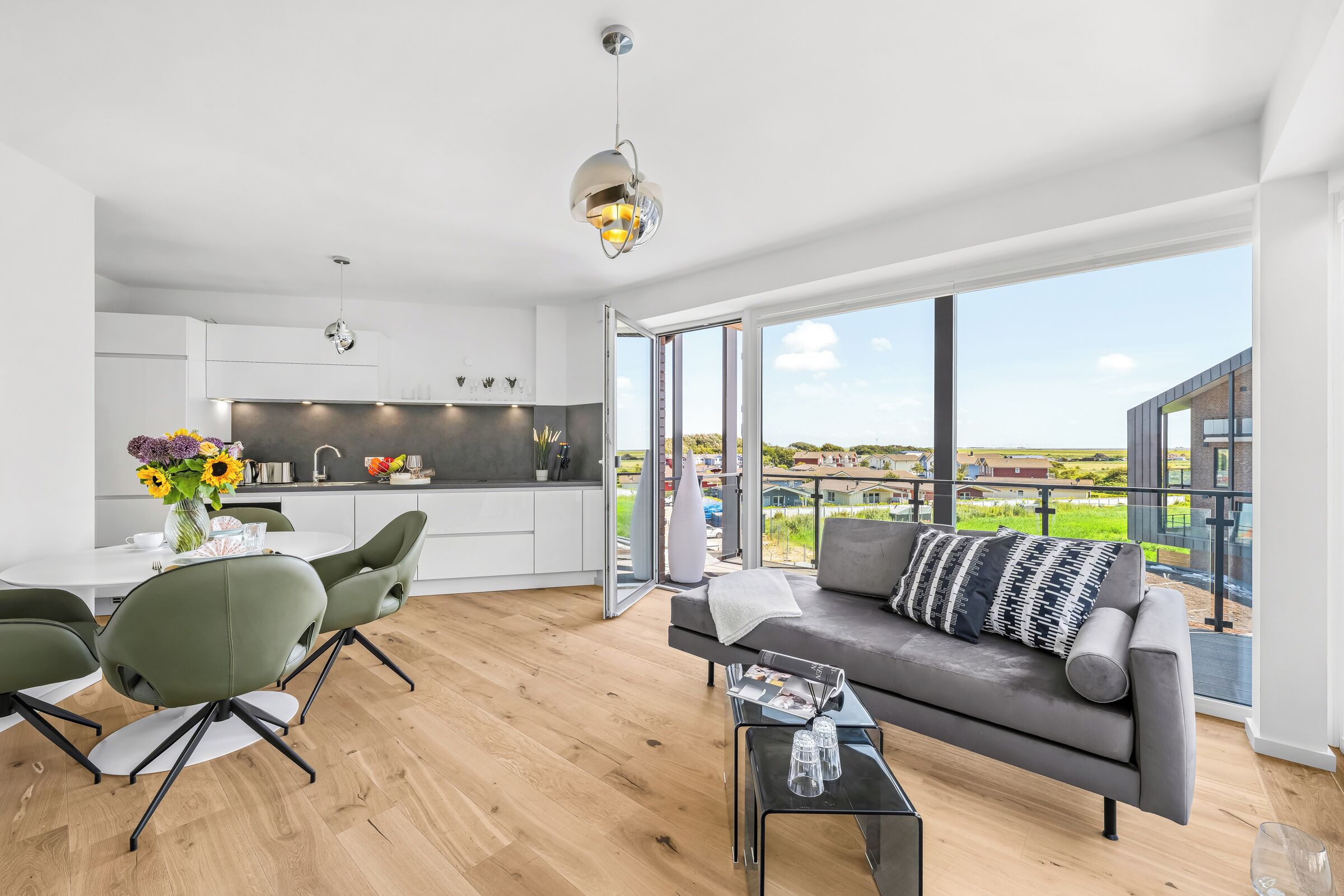Ein zeitgemäßer Wohnraum mit Essbereich, Küche und einem Balkon mit Blick.
