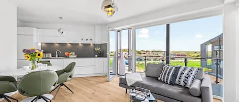 A modern living space with a dining area, kitchen, and a balcony with a view.