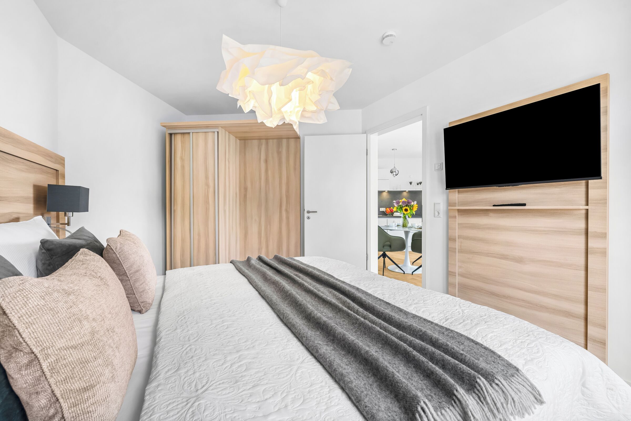 A modern bedroom with a bed, bedside table, lamp, and a television.