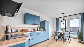 Eine moderne Küche mit blauen Schränken, einer Holzausziehtafel und einem Essbereich inklusive Tisch und Stühlen.
